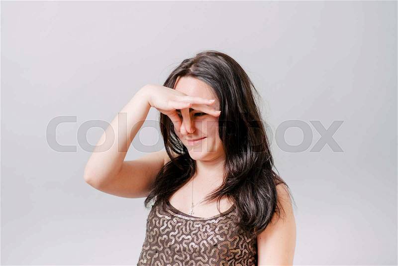 Curly girl covering her nose with his hand, a bad smell. Gray background, stock photo