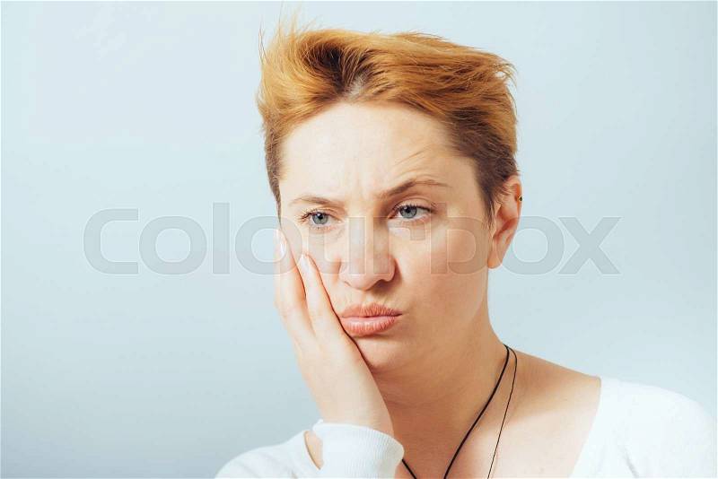 Teen woman pressing her bruised cheek with a painful expression as if she\'s having a terrible tooth ache, stock photo