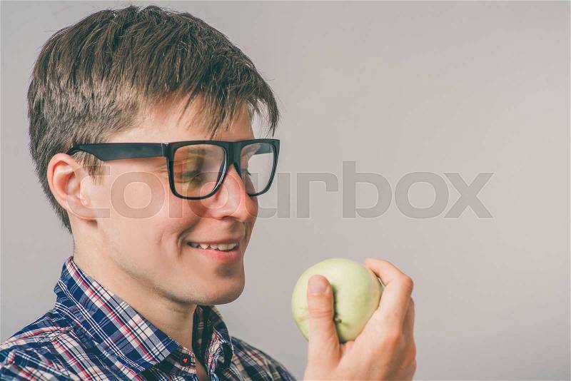Cheerful beautiful man eating apple, stock photo