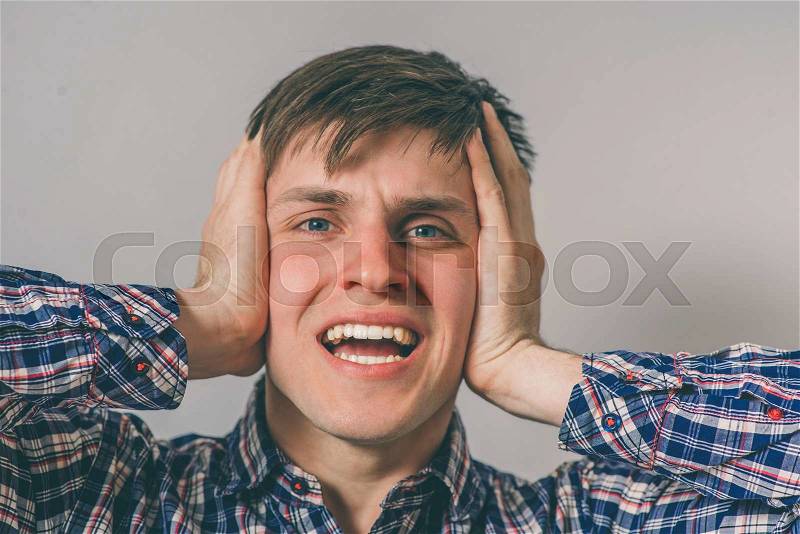 Man covers his ears with his hands, stock photo