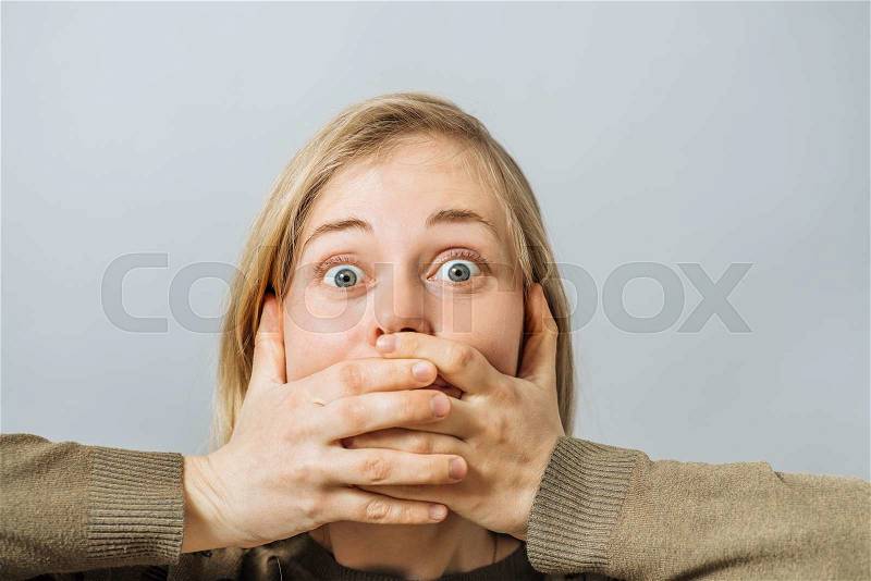 Girl covers her mouth with her hands, stock photo