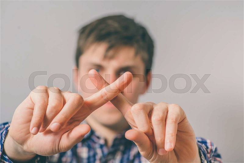 Young man with his fingers crossed, stock photo