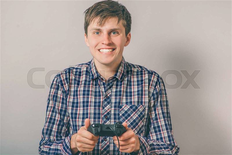 Happy young man in glasses playing video game with joystick over isolated background, stock photo
