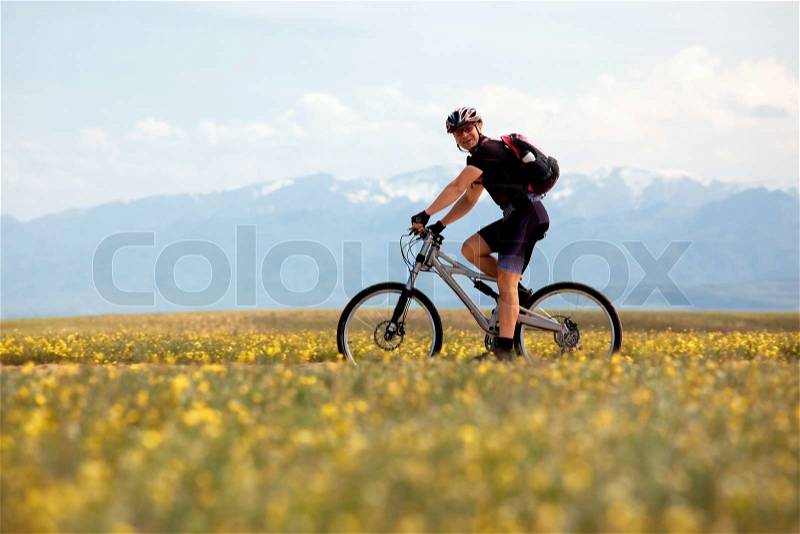 Smiling mountain biker and spring meadow, stock photo