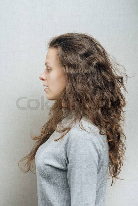 Young serious woman\'s profile. On a gray background, stock photo