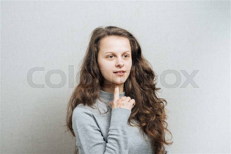 Women think with a serious face. On a gray background, stock photo