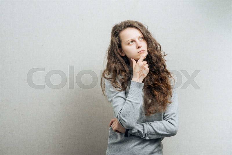 Women think with a serious face. On a gray background, stock photo