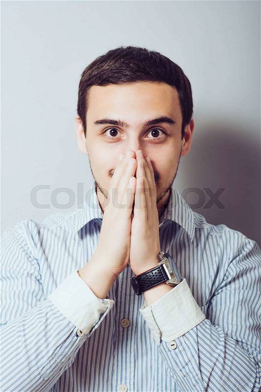 Man covers his mouth with his hands so as not to laugh, stock photo