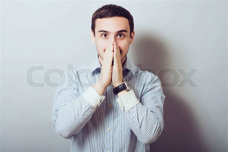 Man covers his mouth with his hands so as not to laugh, stock photo