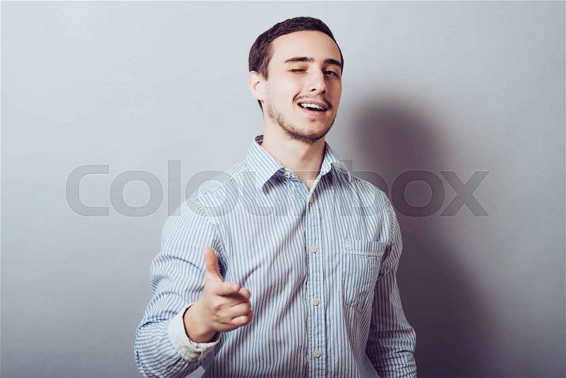 I choose you! Handsome young man in white shirt looking at camera and pointing you while standing against grey background, stock photo