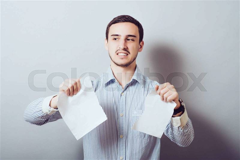 Angry frustrated middle aged man tearing business documents to pieces isolated on grey wall background. Negative human emotions, face expression, feelings, crisis, stock photo