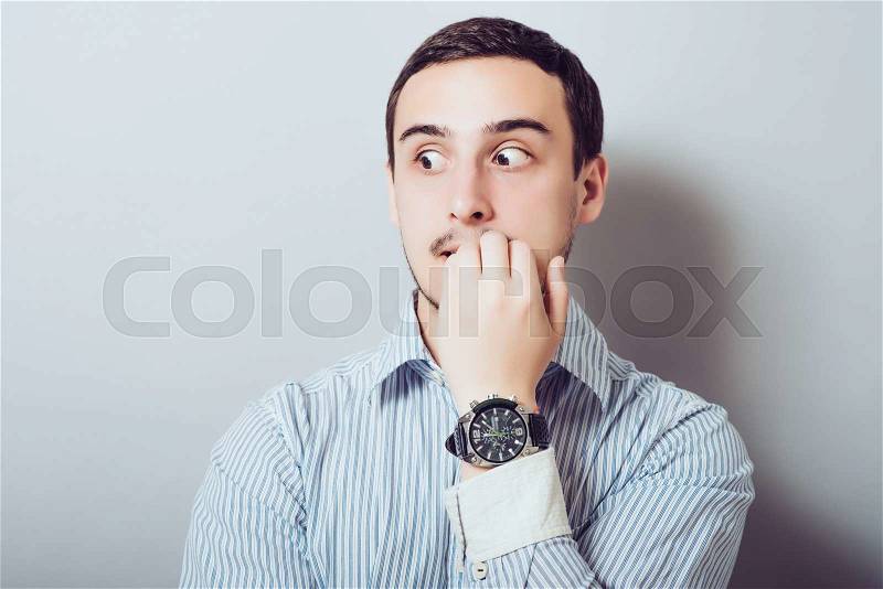 Young business man biting his nails. on a light gray studio background, stock photo