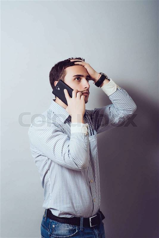 Man talking on the phone and holding his head, stock photo