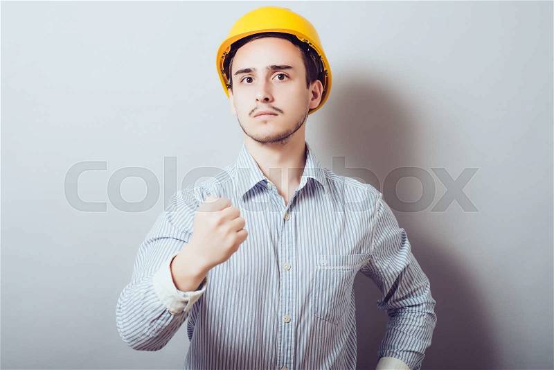 Young construction worker in red shirt wearing yellow hard hat safety equipment raising his fist. Conceptual image: confidence, power, determination; energy; winning; security, stock photo