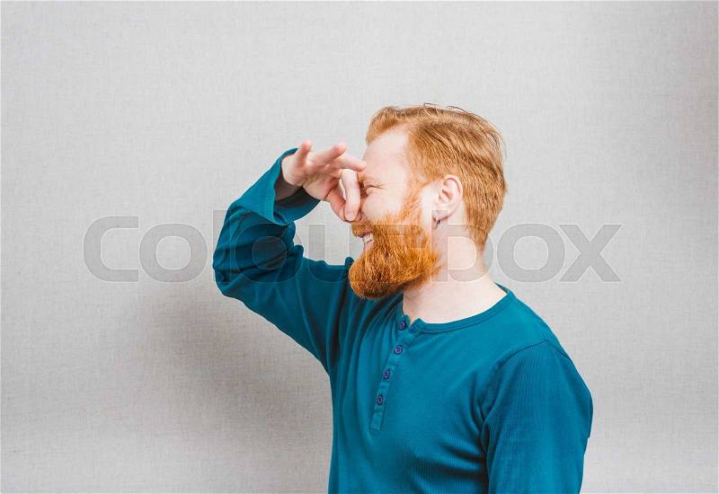 Man holding his nose against a bad smell, stock photo