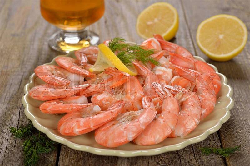 Boiled shrimp with lemon on wooden background, stock photo