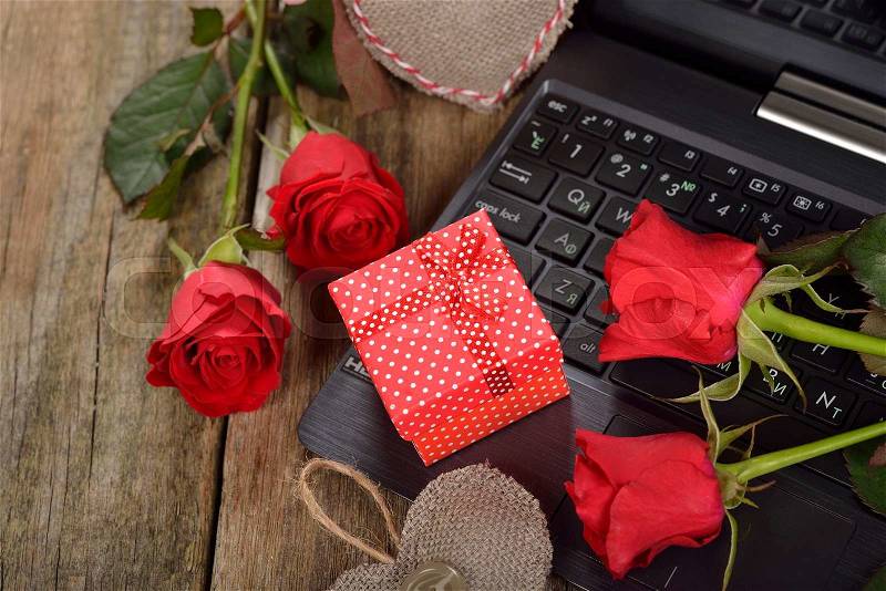 Computer and roses on a wooden background, Valentine's Day concept, stock photo