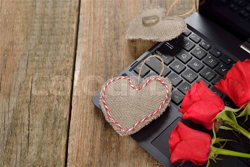 Computer and roses on a wooden background, Valentine\'s Day concept, stock photo