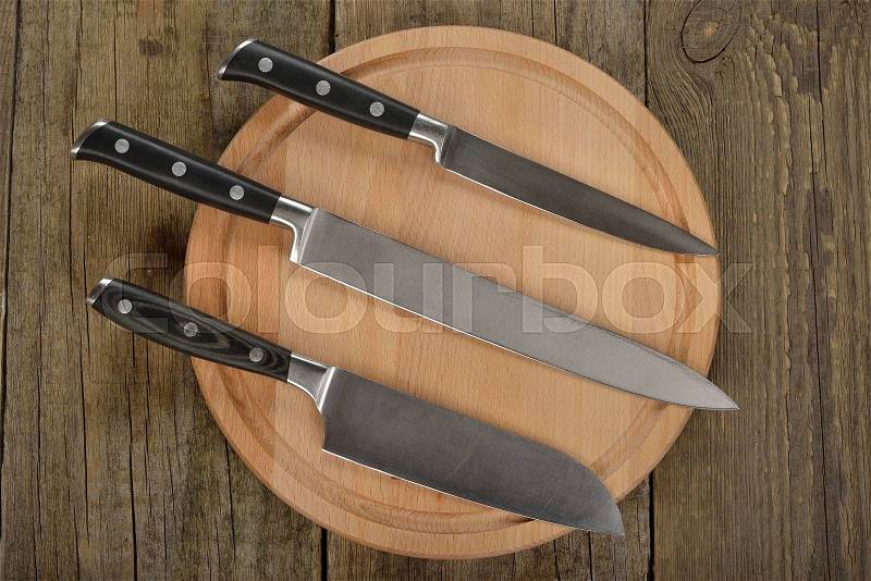 Set of kitchen knives and cutting board on a brown background, stock photo