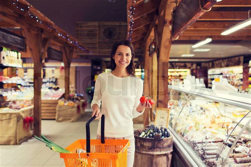 Sale, shopping, consumerism and people concept - happy young woman with food basket and tomatoes in market, stock photo