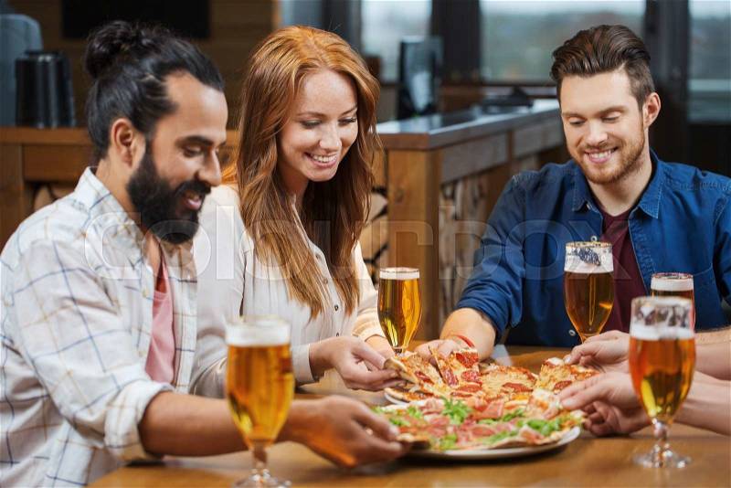 Leisure, food and drinks, people and holidays concept - smiling friends eating pizza and drinking beer at restaurant or pub, stock photo
