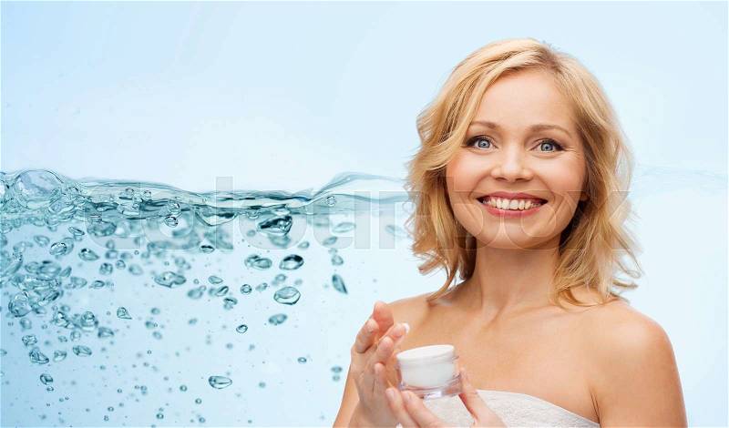 Beauty, people, skincare and cosmetics concept - happy middle aged woman with cream jar over water splash with air bubbles background, stock photo