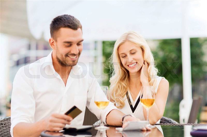 Date, people, payment and relations concept - happy couple with credit card, bill and wine glasses at restaurant terrace, stock photo