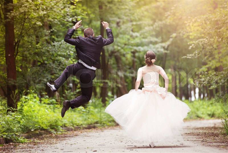 Wedding couple - bride and groom - running down the road, stock photo