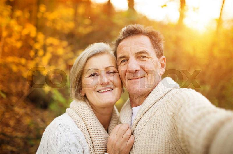 Active seniors taking selfies of them having fun outside in the autumn forest, stock photo