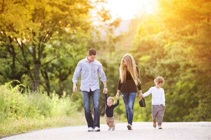 Happy young family walking down the road outside in green nature, stock photo