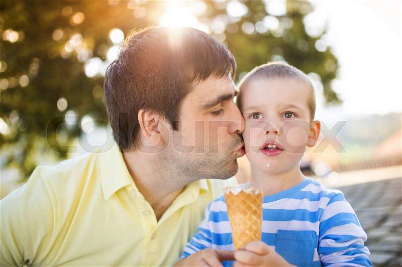 Father and son enjoying ice cream outside in a park, stock photo
