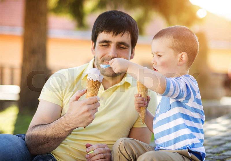 Father and son enjoying ice cream outside in a park, stock photo