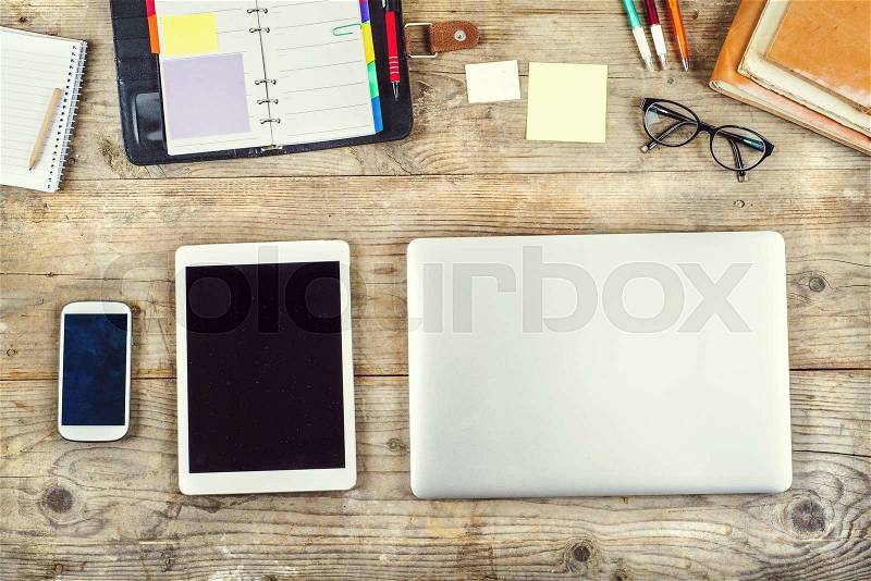 Mix of office supplies and gadgets on a wooden table background. View from above, stock photo