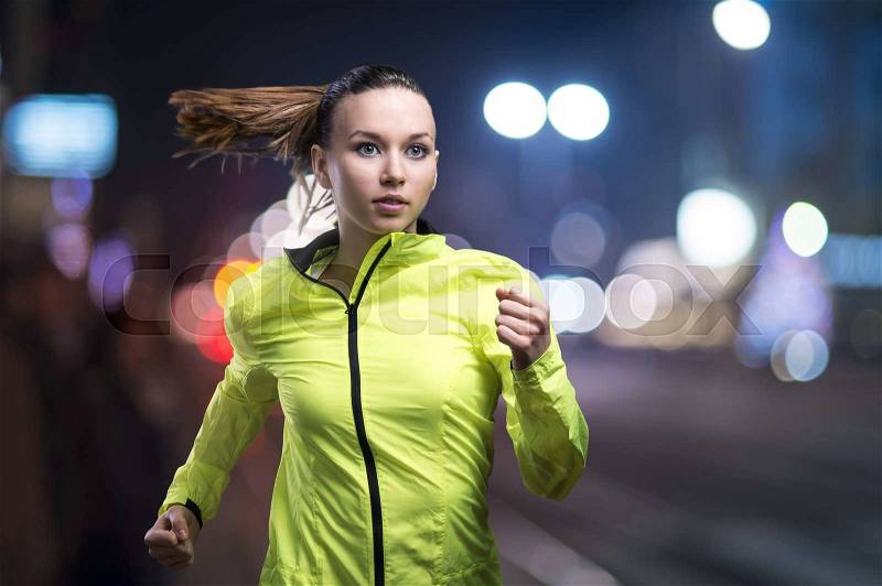 Young woman jogging at night in the city, stock photo
