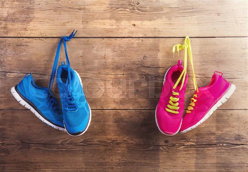 Two pairs of sneakers hang on a nail on a wooden fence background, stock photo