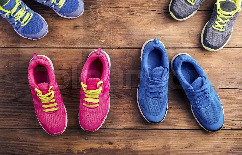 Four pairs of various running shoes laid on a wooden floor background, stock photo