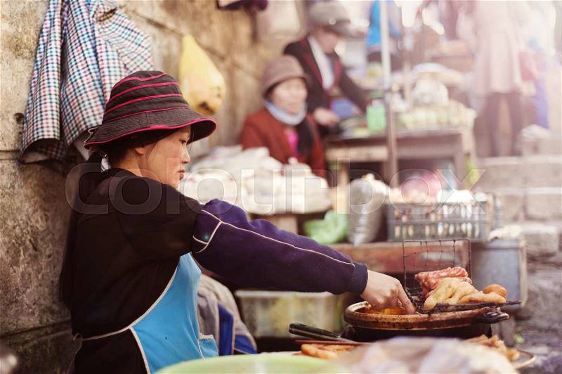 Asian woman selling sausages on traditional street market in Sapa, Vietnam, stock photo