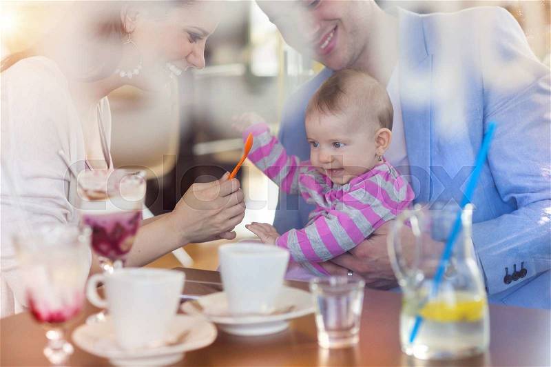 Beautiful young family having fun in cafe, stock photo