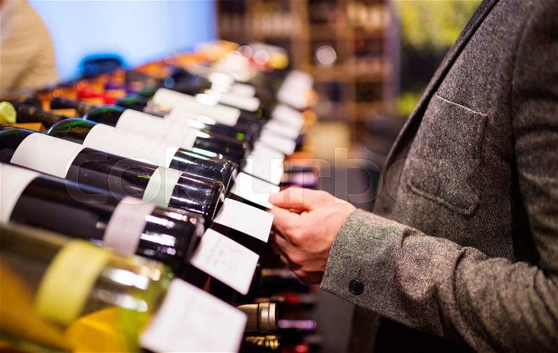 Unrecognizable young man in a wine shop choosing a wine, stock photo