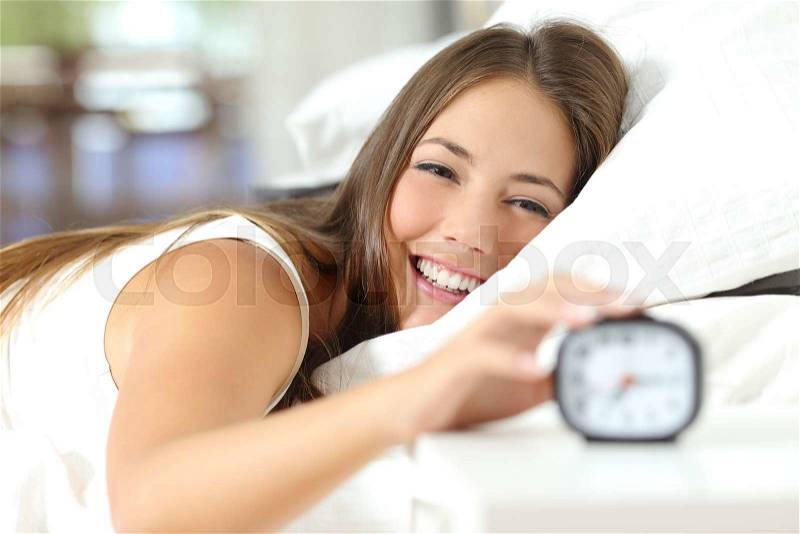 Happy woman waking up and turning off the alarm clock having a good day, stock photo