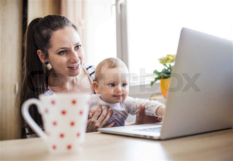 Young mother in home office with computer and her daughter, stock photo