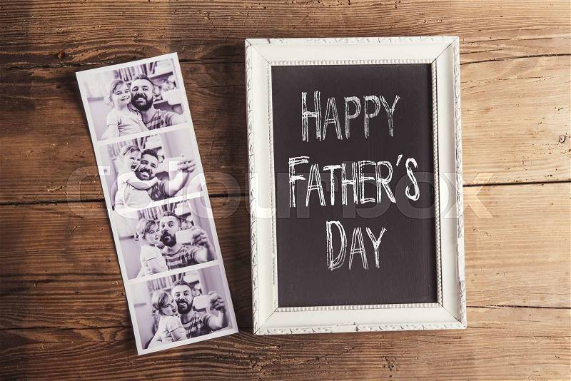 Picture frame with Happy fathers day sign and instant photos on wooden background, stock photo