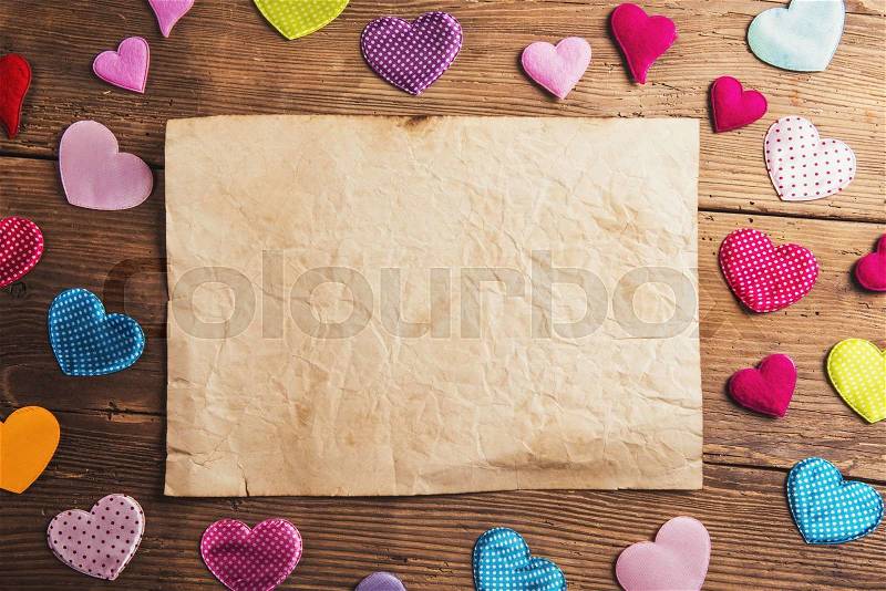 Empty paper sheet and colorful fabric hearts. Studio shot on wooden background, stock photo