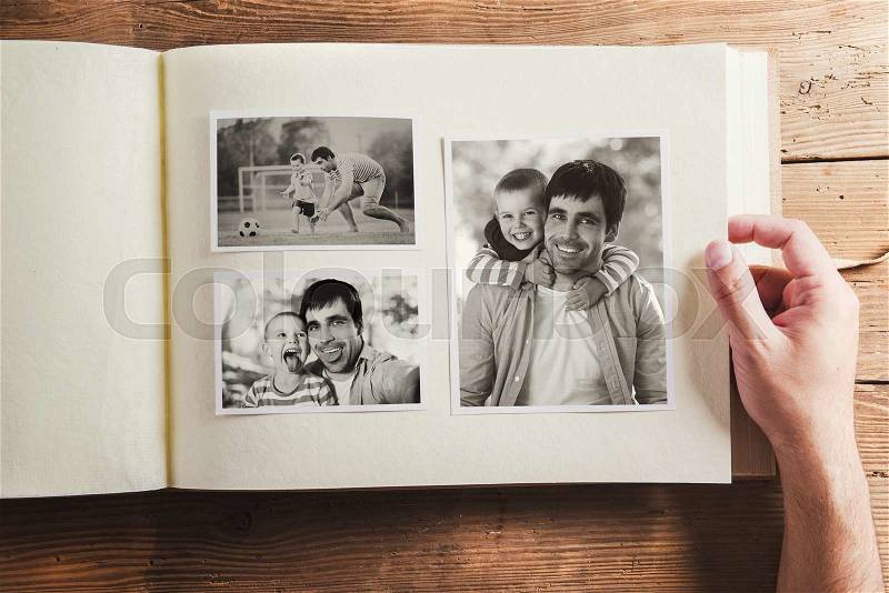 Photo album with black and white family pictures. Studio shot on wooden background, stock photo