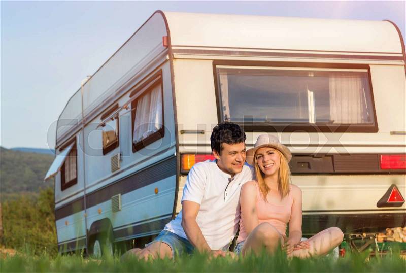 Beautiful young couple in front of a camper van on a summer day, stock photo