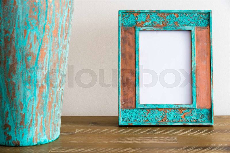 Vintage photo frame on wooden table over white wall background with empty white canvas, copy space available, stock photo
