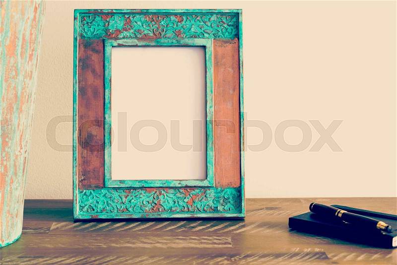Vintage photo frame on wooden table over white wall background with empty white canvas, copy space available, stock photo