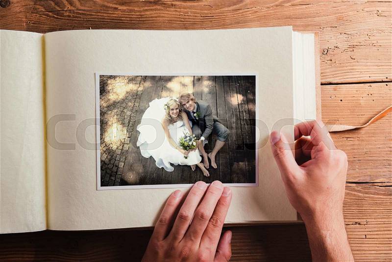 Picture of bride and groom in photo album. Studio shot on wooden background, stock photo