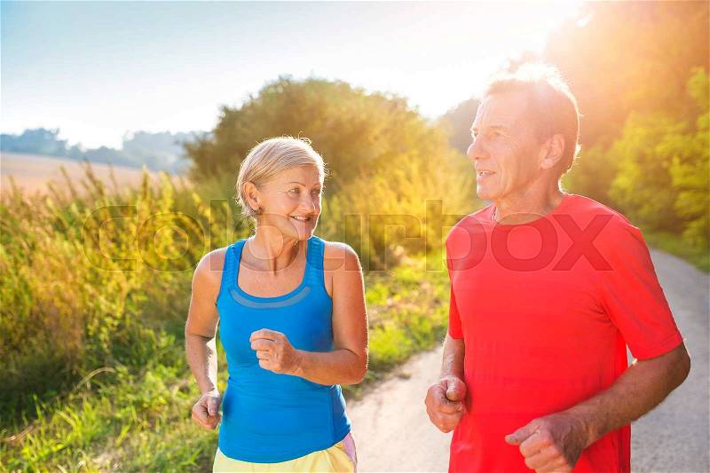Active seniors running outside in green nature, stock photo