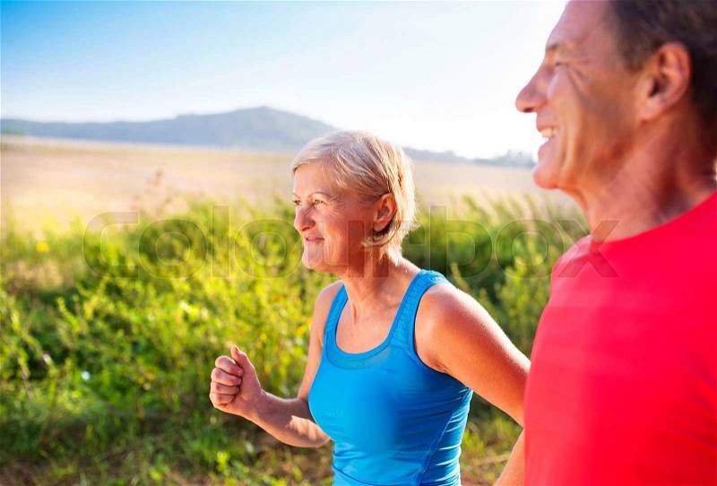 Active seniors running outside in green nature, stock photo